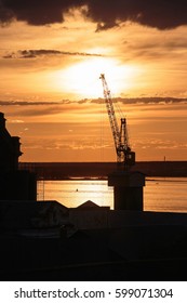 Small harbor crane used for loading ships. Photo at sunset