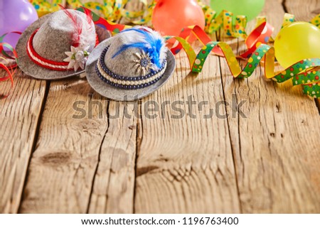 Small hats with feathers stuck in them and round multicolored balloons sitting on rustic wooden table