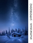 Small hay barn and epic milky way at winter morning blue hour covered by snow in Finland