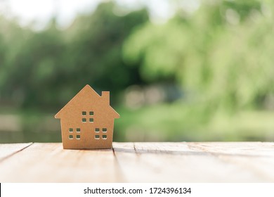 Small Home Model On Wooden Table With Nature Green Bokeh Abstract Background. Family Life And Business Real Estate Concept. Vintage Tone Filter Effect Color Style.