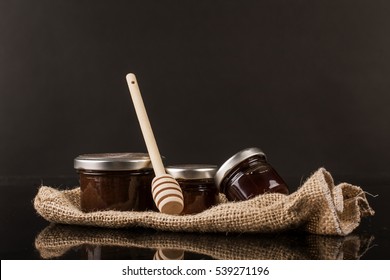 Small Honey Jars On A Black Background