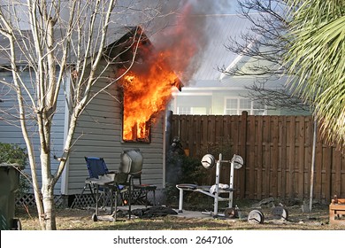 Small House Ablaze With Fire Blowing Through Windows