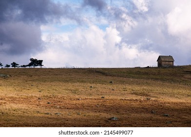 A Small House Or Agricultural Building On The Horizon On The Aubrac Plateau Lozere , France . Showing Stormy Big Sky