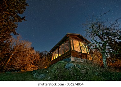 Small House With Big Orange Windows And A Bright Starry Night Sky. Sweden