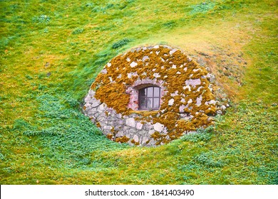 A small house in the ground with a small window. Hobbit house