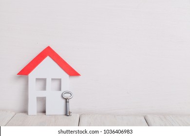 Small house with key over white wood an white background. - Shutterstock ID 1036406983