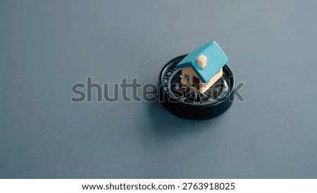 Small house model placed directly on a compass representing the search for a home or finding the perfect location for property.