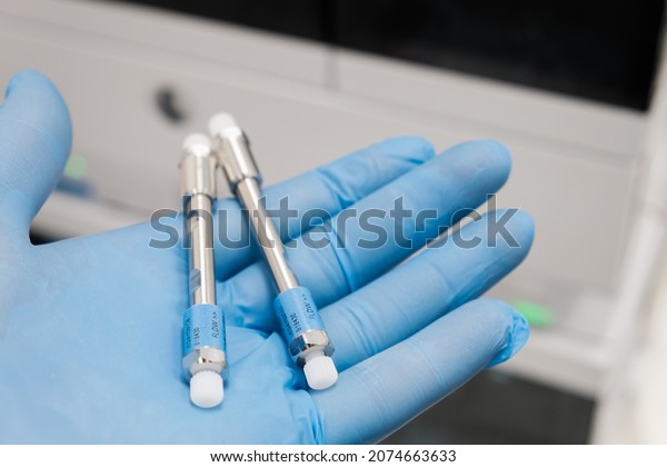 Small HPLC 50 mm columns for separation\
compounds in laboratory worker hand in rubber glove. Fast high\
performance liquid chromatography analysis in chemical and\
microbiological laboratory.\
Clinical
