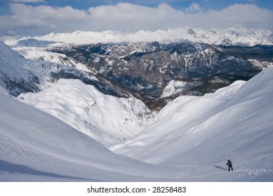 Small human walking on the snow covered mountains