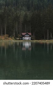Small hut in the Italian Dolomites with a green forest in the back. Moddy evening with wiew on the lake Dobbiaco, South Tyrol, Italy, Europe. 