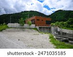 Small hydroelectric dam operates in a forested area, exemplifying sustainable energy production.