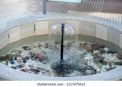 Small Indoor Fountain In A Pool With Decorative Stones, Pebbles And Rocks. Clean Water