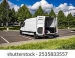 Small Industrial carrier compact white maneuverable and economical cargo mini van make delivery to the customer standing with open back doors on the parking lot for a cargo unload