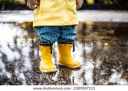 Similar – Image, Stock Photo Small infant boy wearing yellow rubber boots and yellow waterproof raincoat standing in puddle on a overcast rainy day. Child in the rain.