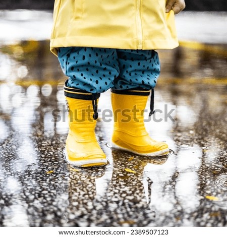 Image, Stock Photo Small infant boy wearing yellow rubber boots and yellow waterproof raincoat standing in puddle on a overcast rainy day. Child in the rain.