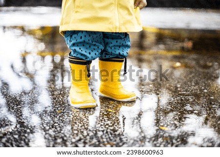 Similar – Image, Stock Photo Small infant boy wearing yellow rubber boots and yellow waterproof raincoat standing in puddle on a overcast rainy day. Child in the rain.