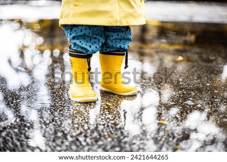 Similar – Image, Stock Photo Small infant boy wearing yellow rubber boots and yellow waterproof raincoat standing in puddle on a overcast rainy day. Child in the rain.