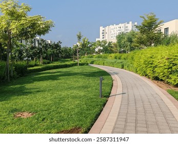 Small Interlock Path Between Landscaping Area.
Green And Lush Landscaping Area With Carpet Grass And Trees Like Palm Or Washingtonia, Some Houses Or Villa's Also Beside Gardens Padestrian Pathway.
