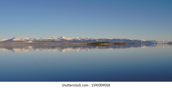 A small island filled with trees sits in Yellowstone Lake on a beautiful still day. - Powered by Shutterstock