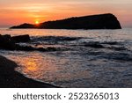 A small island with green plants and a blue sky with beautiful clouds, an island in the Mediterranean Sea near a sandy beach and coast and an azure sea in the state of Jijel, Algeria, North Africa.