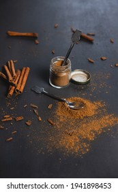 Small Jar Full Of Ground Cinnamon With A Tiny Spoon Inside And Cinnamon Sticks On The Side. On Black Background. Ceylon Cinnamon, Healthy Spice.