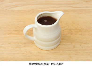 Small Jug Of Gravy On A Wooden Board