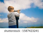 Small kid exploring the sky through coin operated binoculars. Copy space.