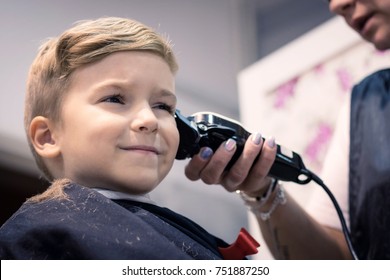 Small kid getting a haircut at barber shop. - Powered by Shutterstock