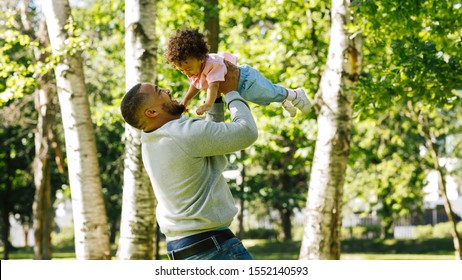Small kid playing and having fun with his father in a park on a sunny day