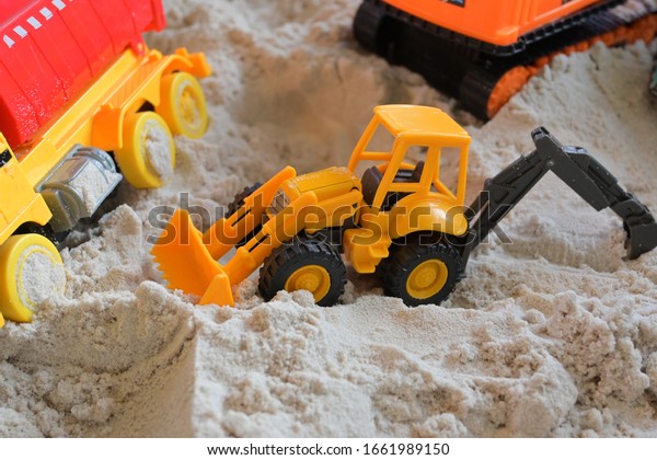 small kid\
toy vehicle construction in sand\
playground