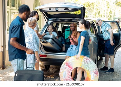 Small kid travelling on vacation with family, preparing to go to seaside holiday during summer. Diverse people and friends loading suitcase and trolley in car trunk, leaving on journey trip. - Powered by Shutterstock