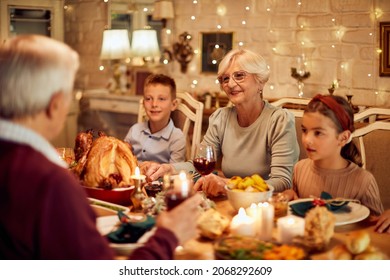 Small Kids And Their Grandparents Communicating During Thanksgiving Dinner At Dining Table. Focus Is On Senior Woman. 