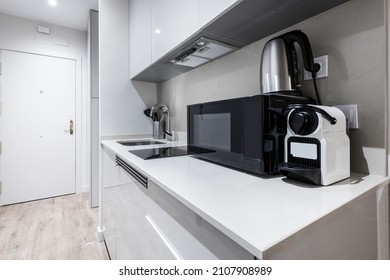 small kitchen of a gray apartment with microwave, water fort and coffee capsule machine - Powered by Shutterstock