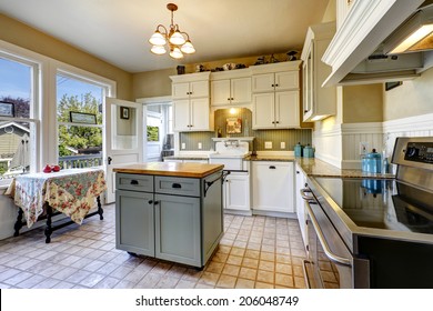 Small Kitchen Interior With White Wooden Cabinets, Tile Floor And Kitchen Island