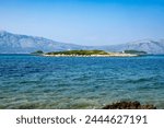 Small Knezic island, near the shore of lumbarda, small town on Korcula island with mighty Peljesac peninsula rising across the sea on croatian coast