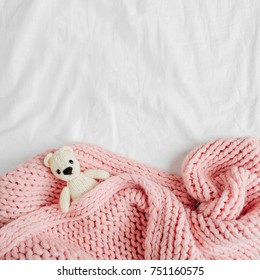 Un piccolo orsetto giocattolo lavorato a maglia è coperto con una coperta calda, laici piatti, vista dall'alto Foto stock