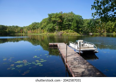 Small lake in northern Minnesota with a dock and pontoon boat on a sunny clear day