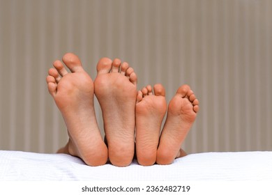 Small and large bare feet, two pairs of barefoot close-up, children lying on the bed. Foot Relaxing. Togetherness and Growing up concept. Childhood moments. - Shutterstock ID 2362482719