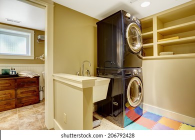 Small Laundry Area In Bathroom. View Of Black Modern Appliances