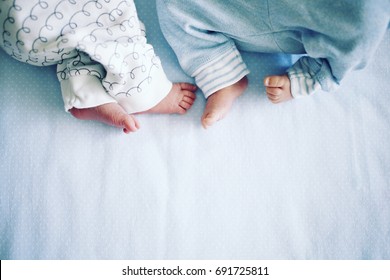 Small legs of two newborn twins in panties on a blue background. Happy Family concept. Beautiful conceptual image of Maternity