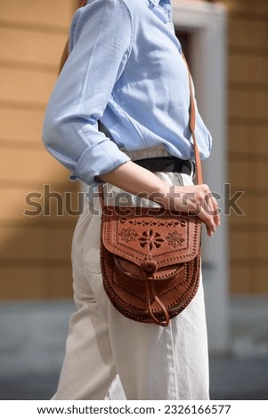 small light brown women's leather bag with a carved pattern. selective focus