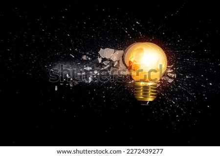 small light bulb exploding against a black background
