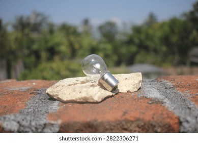 Small Light Bulb on Brick and Stone with Nature Background