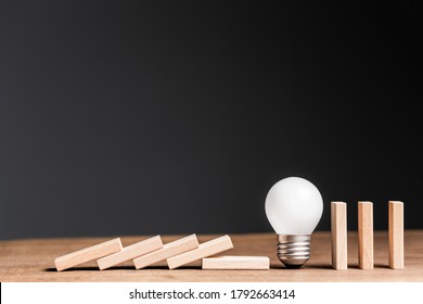 Small light bulb in a row of wooden domino, stop the falling domino, problem and solution or creativity concept