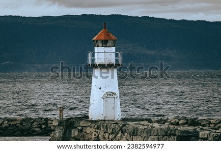 A small lighthouse over a fjord at Trondheim in Norway. Sunset - fiery sky.