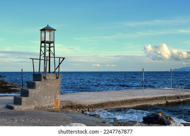 Small lighthouse with stairs and concrete pier during sunset near Monemvasia, Greece