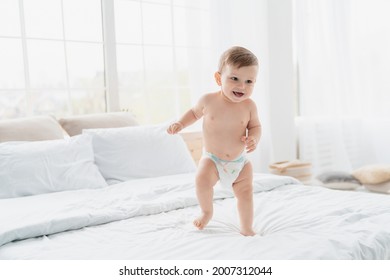 Small little caucasian baby newborn infant making first steps, cute toddler kid child girl son boy daughter learning walking creeping on the bed. Childcare and childhood concept