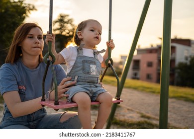 Small Little Girl Toddler With Her Mother In Park Woman Help Her Child To Swing While Having Fun Outdoor In Sunny Day Leisure Family Growing Up Concept Copy Space Real People