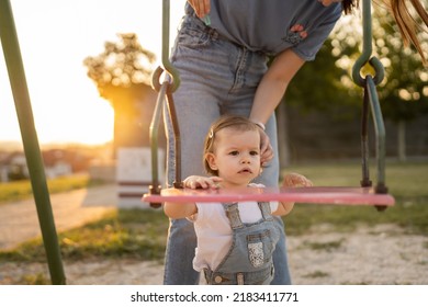 Small Little Girl Toddler With Her Mother In Park Woman Help Her Child To Swing While Having Fun Outdoor In Sunny Day Leisure Family Growing Up Concept Copy Space Real People