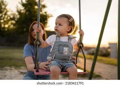 Small Little Girl Toddler With Her Mother In Park Woman Help Her Child To Swing While Having Fun Outdoor In Sunny Day Leisure Family Growing Up Concept Copy Space Real People